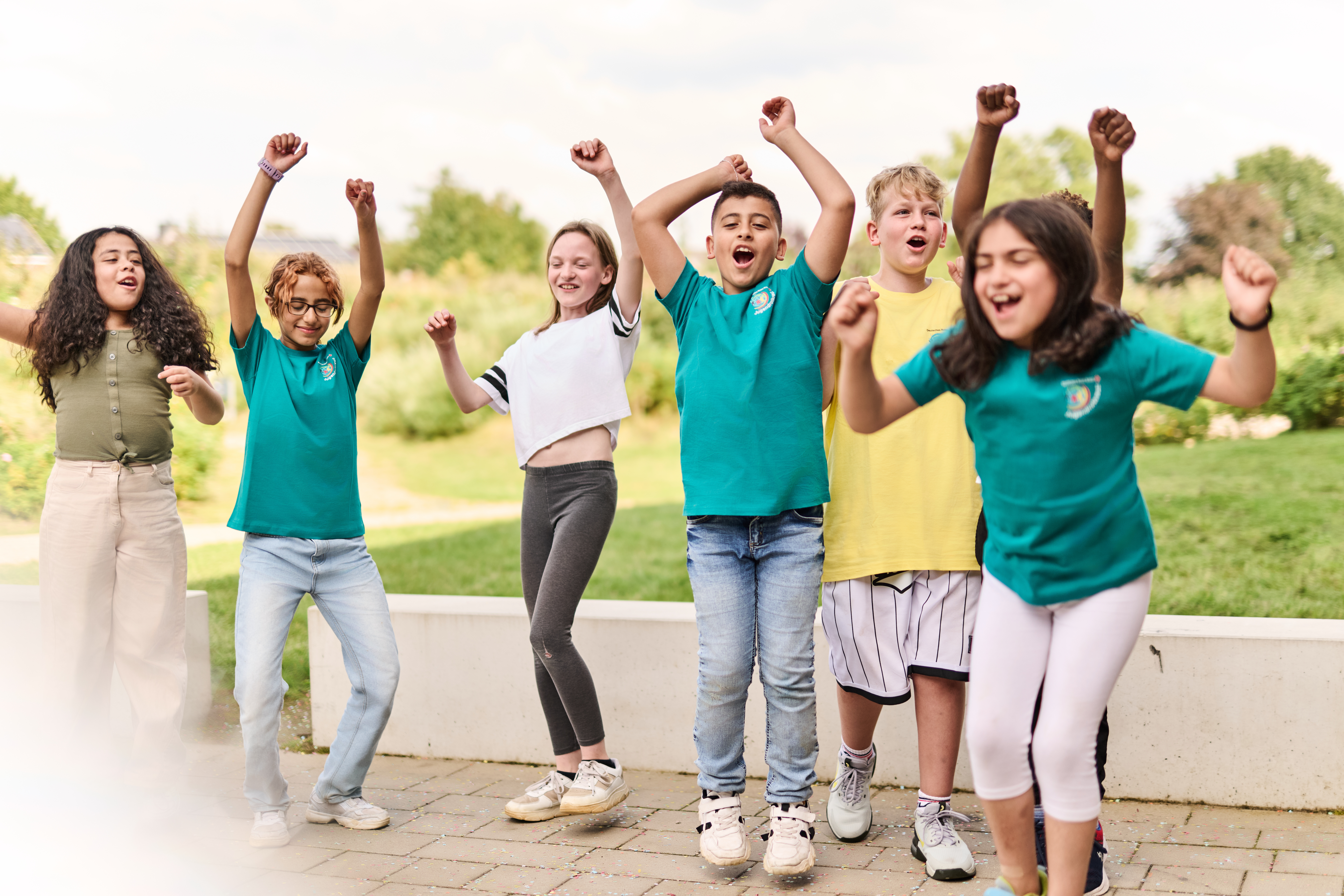 Sechs jubelnde Kinder von etwa 9 Jahren. Im Hintergrund Wiese