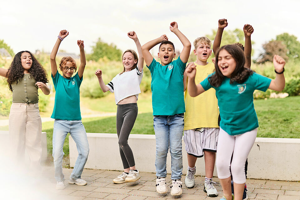 Sechs jubelnde Kinder von etwa 9 Jahren. Im Hintergrund Wiese